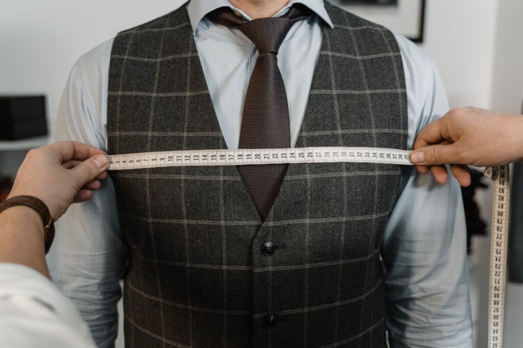 pexels photo 6766283 A tailor measuring a client's chest for a bespoke suit in a professional setting.